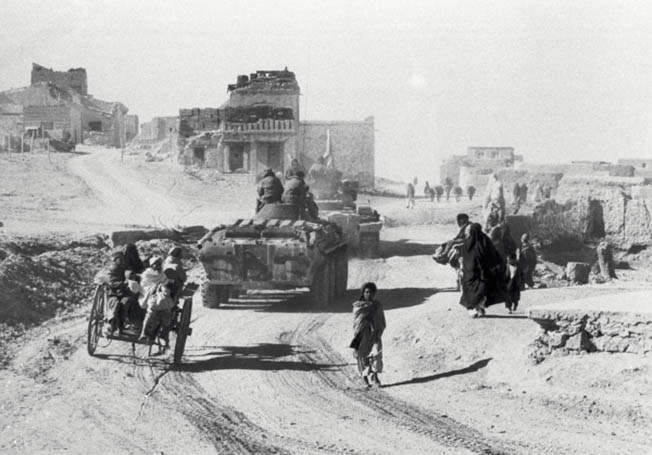 Советская военная техника едет по улице кишлака в Афганистане.