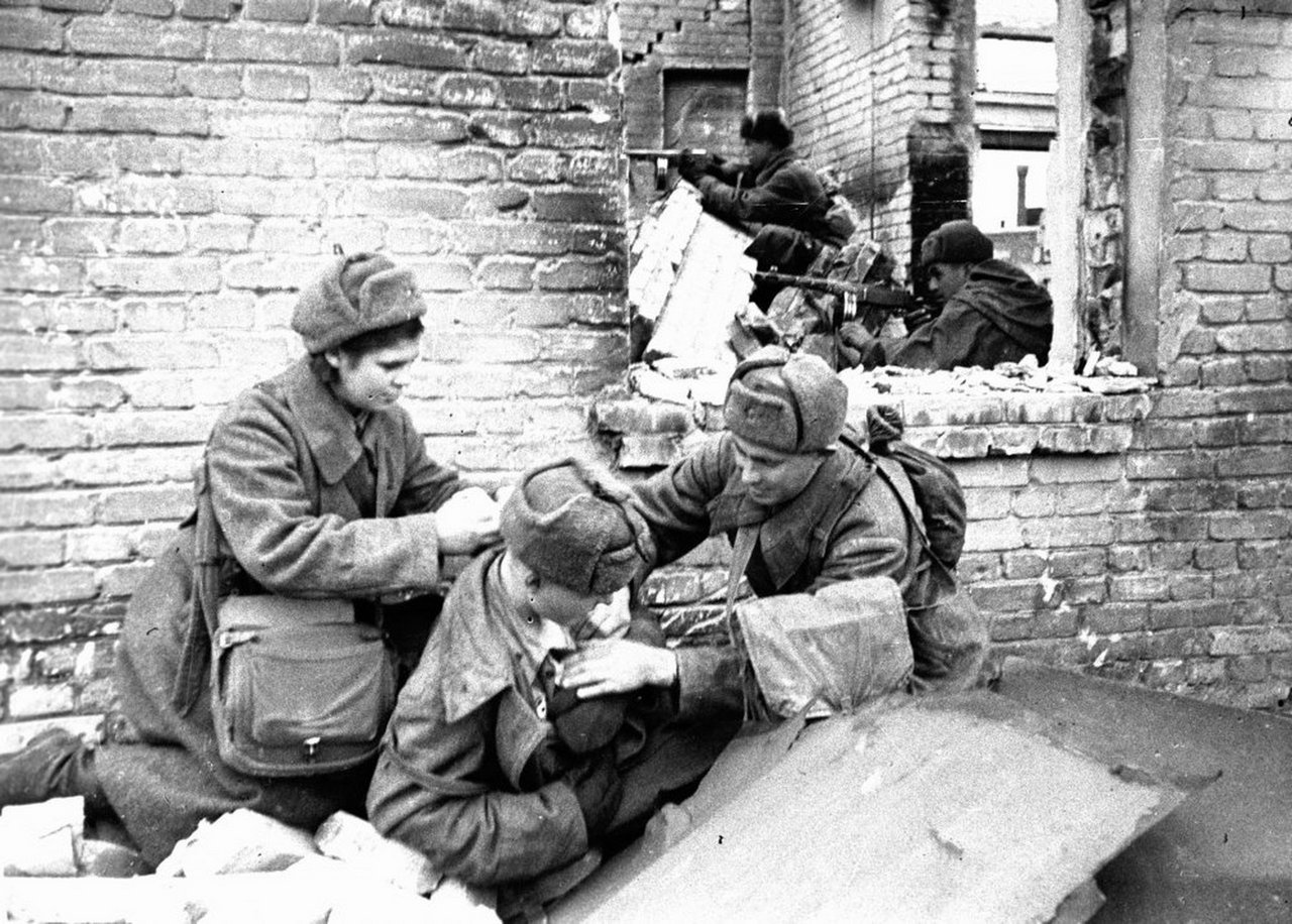 Санинструкторы перевязывают раненого бойца в Сталинграде.