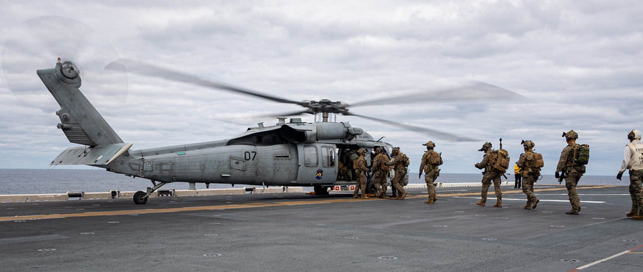 Морские пехотинцы США поднимаются на борт вертолёта Seahawk на лётной палубе десантного корабля USS America во время учебных полётов в Филиппинском море, 10 февраля 2025 г.