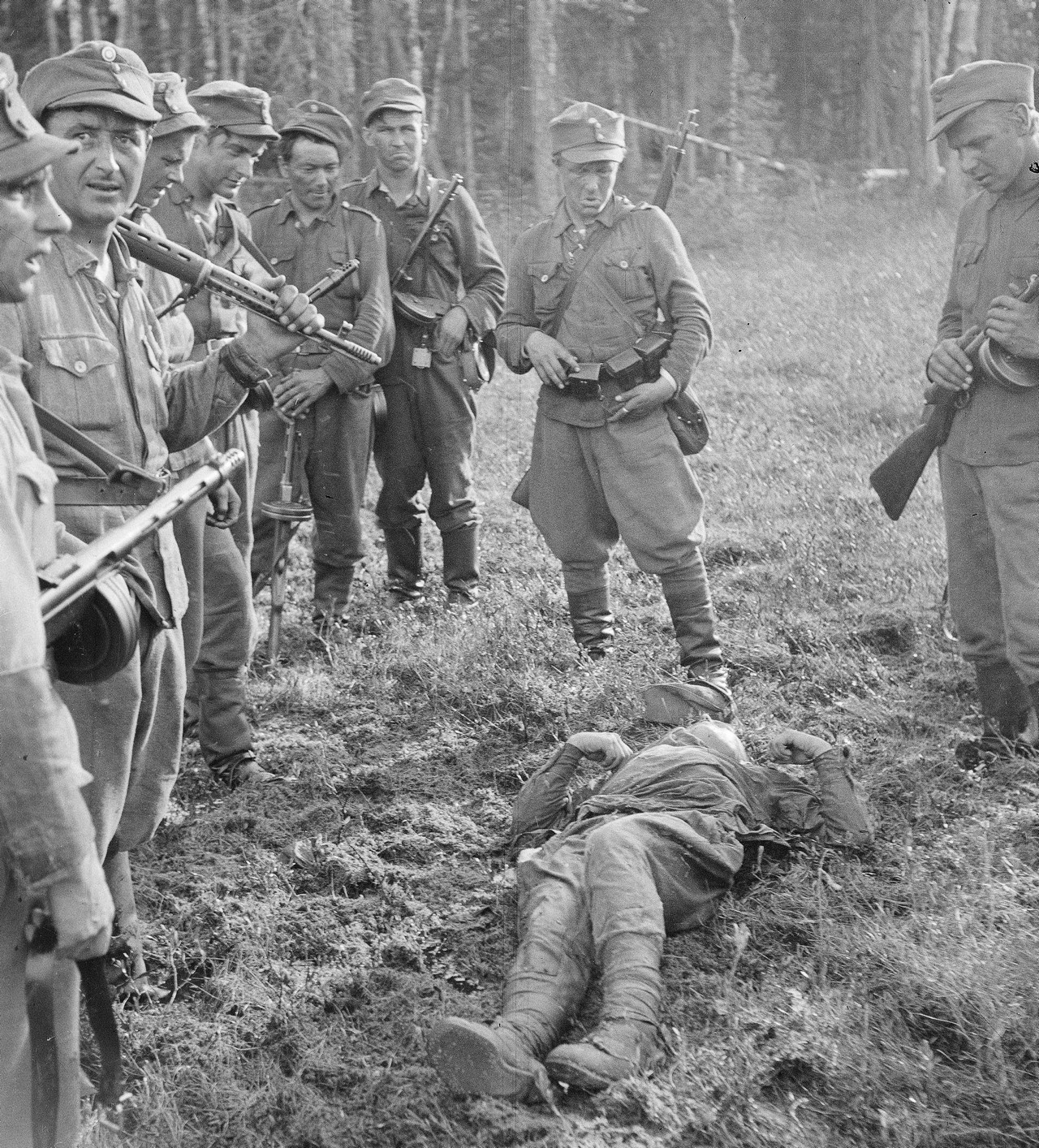 Финские солдаты у тела красноармейца, погибшего на берегу реки Охта на севере Карелии, июнь 1944 г.