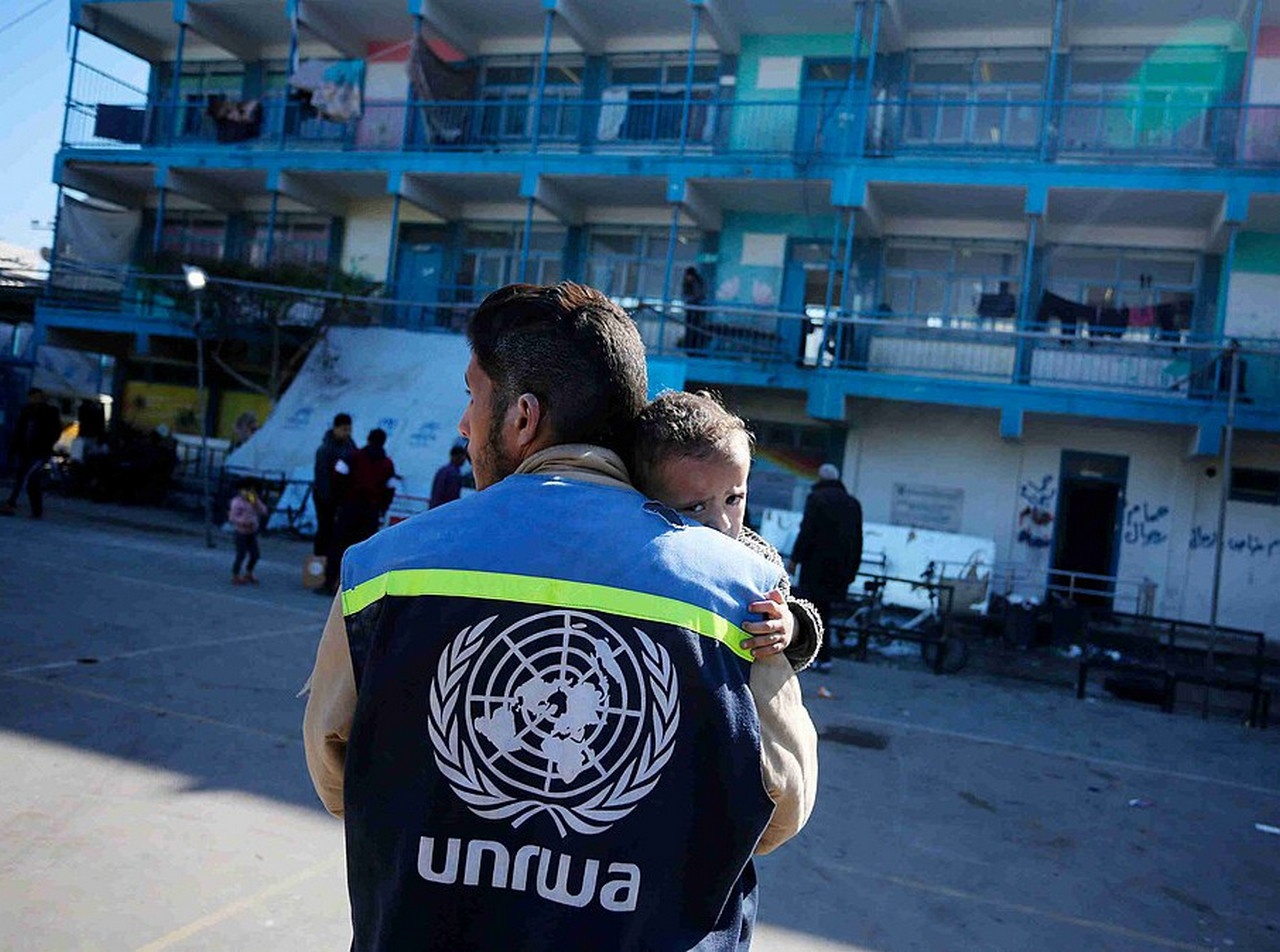Сотрудник БАПОР успокаивает ребёнка в школьном приюте в лагере Нусейрат.