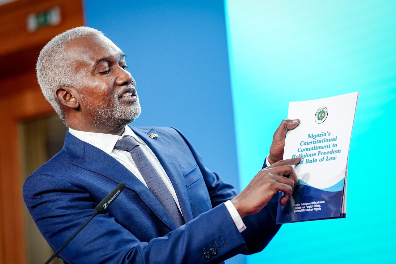 Юсуф Туггар демонстрирует брошюру «Конституционное обязательство Нигерии в отношении религиозной свободы и верховенства закона» после вопроса журналистов о реакции на заявление президента США, 4 ноября 2025 г.