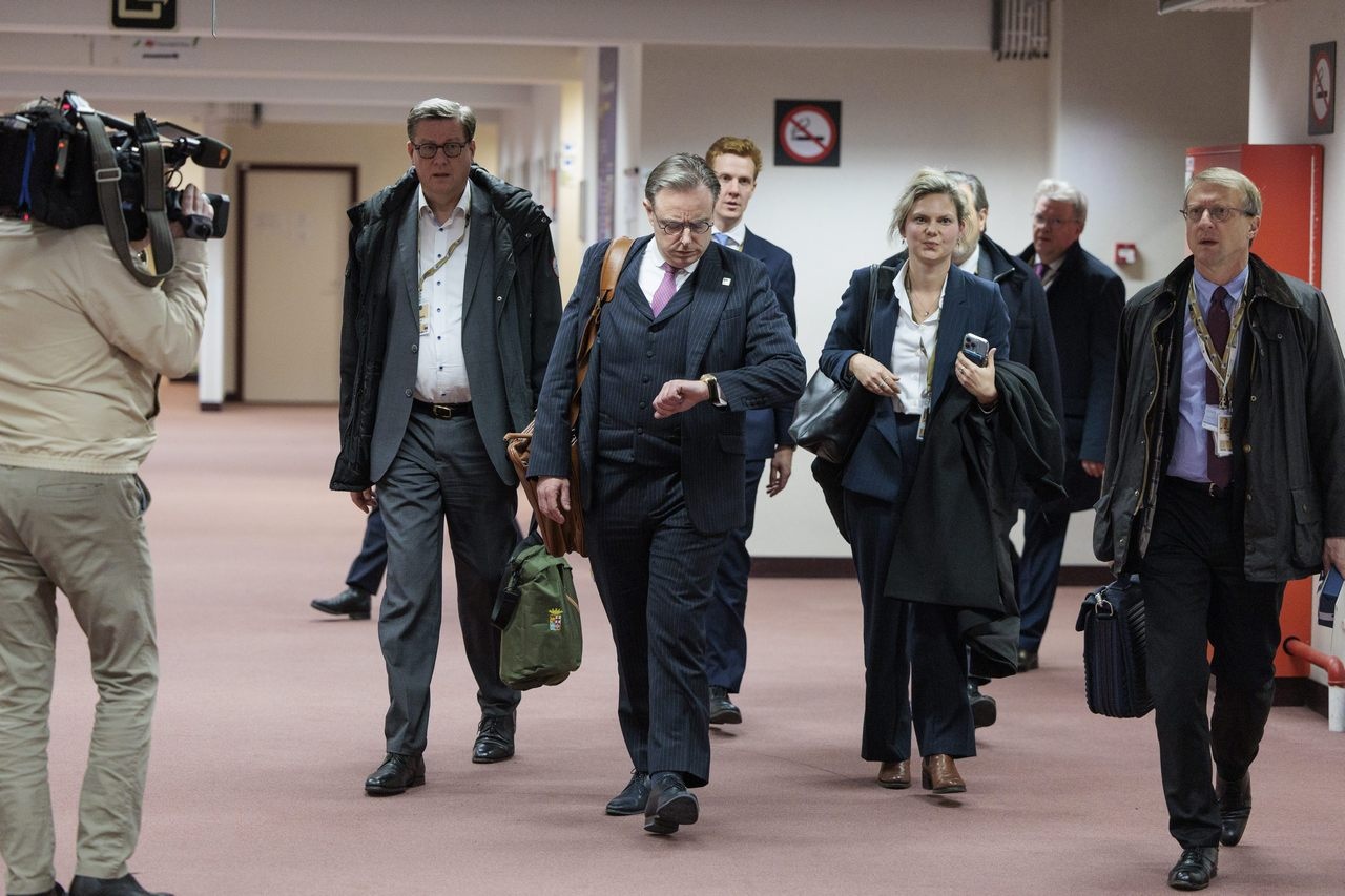 Премьер-министр Бельгии Барт де Вевер (в центре) проверяет, сколько времени осталось до вызова в суд для ответа на иски России.